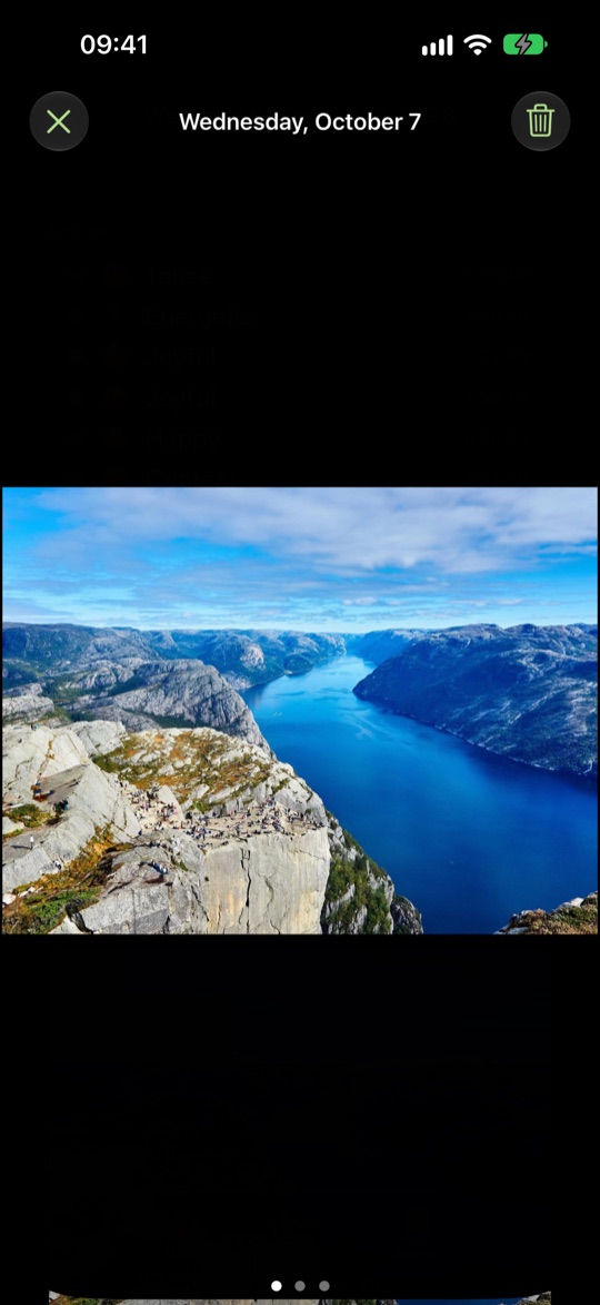 A photo in full screen, a blue fjord between rocky slopes, with the date, close and trash buttons at the top and three dots for three photos that day.